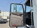 The open door of a 2020 Peterbilt 330 truck revealing the driver's cabin and control panel