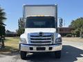 A white 2020 Hino 338 truck with a boxy cargo area and chrome grille facing directly towards the viewer