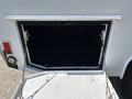 A 2017 Ford F-550 service box with an open compartment showing a dark interior and two metal hinges attaching the lid