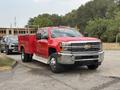 A red 2015 Chevrolet Silverado 3500HD pickup truck with a utility bed is parked in a lot