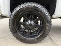 A black wheel with a muscular design and thick treads, featuring the Goodyear and Nitto tire brands, attached to a Chevrolet Silverado 1500