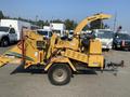 A yellow Vermeer Corporation BC1200XL wood chipper with a funnel-like chute on top and various controls and markings on the side