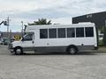 A 2020 Chevrolet Express bus with a white exterior and large windows is parked sideways, featuring a raised roof and a gray lower panel