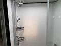 A glass shower enclosure featuring a rainfall showerhead two shower caddies for storage and bright white walls