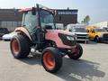 A pink 2010 Kubota M6040 tractor featuring large tires and a cabin with a clear windshield