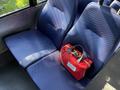 A red bag is placed on a blue upholstered seat inside a vehicle