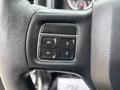 Close-up of a steering wheel control panel featuring four buttons arranged in two rows for adjusting settings