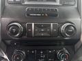 Dashboard controls of a 2017 Ford F-150 featuring knobs for volume and tuning digital display and air conditioning settings