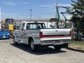 A 1995 Ford F-250 pickup truck with a silver exterior and red stripe details parked in an outdoor area