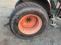A large rear tire of a 2010 Kubota M6040 tractor with a rugged tread and an orange rim visible with a central axle hub