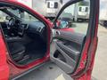 A red 2015 Jeep Grand Cherokee with the driver's door open showing the interior features and dashboard
