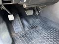 Close-up of the footwell in a 2018 Toyota Highlander showing the pedals and a weather-resistant floor mat featuring the Toyota logo