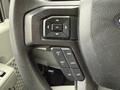 Close-up of the steering wheel buttons in a 2024 Ford E-450 featuring controls for navigation and cruise settings