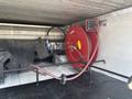 A red hose reel mounted inside a utility compartment with a black hose and fittings visible along with various tools and equipment