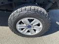 Close-up of a Ford F-150 tire featuring a rugged tread pattern mounted on a silver alloy wheel
