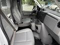 Interior of a 2017 Ford Econoline showing two front seats a dashboard with controls and a center console with cup holders