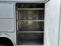 A 2024 Ford F-550 with an open storage compartment featuring three metal shelves and a smooth interior surface