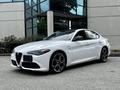 A 2023 Alfa Romeo Giulia in white with distinctive front grille large wheels and sporty design parked in a commercial area