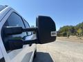 Close-up of a side mirror on a 2023 Ford F-350 SD truck with a black housing and an integrated light