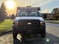 A 2006 Ford F-550 truck facing the camera with a white body and a black grille featuring round headlights and a yellow light bar on top