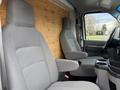 Interior of a 2022 Ford E-450 featuring two gray cloth seats with armrests and a center console with cup holders