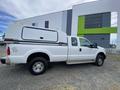 A white 2014 Ford F-350 SD truck with an extended cab and a covered bed designed for storage