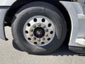 A close-up of a tire mounted on a 2022 Freightliner Cascadia featuring large lug nuts and a strong tread pattern