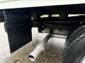 A 2024 Ford E-450 with a visible exhaust pipe and black undercarriage components on a wet surface