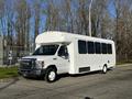 A white 2014 Ford Econoline passenger van with large windows parked on a street