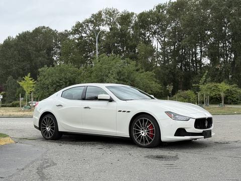 A 2016 Maserati Ghibli in white with a sleek design featuring red brake calipers and black alloy wheels