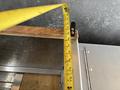 A measuring tape extends from the edge of a wooden surface attached to the metallic body of a 2011 Workhorse W62 vehicle