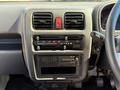Dashboard of a 2009 Suzuki Carry featuring air conditioning controls a radio and a digital clock