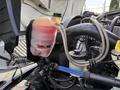 A close-up of the engine compartment of a 2011 International 4300 featuring a transparent coolant reservoir filled with fluid and various hoses and components connected to the engine