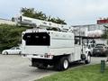 A 2006 International 4300 truck with an Altec aerial lift mounted on the back and a boxy utility body in white color