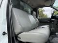 The interior of a 2004 Ford F-750 showing a gray bench seat with a textured surface and a gear shift lever visible in the foreground