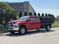 Red 2013 RAM 2500 pickup truck with a flatbed and a black mesh trailer attached parked on a paved surface
