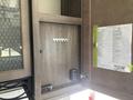 A wooden cabinet door is open revealing a rack for keys and a laminated list of features or inventory attached to the inside of the door