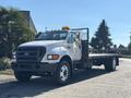 A 2004 Ford F-750 flatbed truck with a white exterior and black grille parked on a street