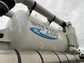 A white Vactor 2100 vacuum truck with a rounded tank and a large pipe system mounted on top