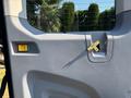 The interior door panel of a 2016 Ford Transit 150 featuring a yellow latch and a rectangular button in red and green