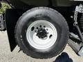 Close-up of a 2012 Autocar XPERT tire showcasing a black tread pattern mounted on a white wheel with visible lug nuts and a valve stem