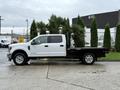 White 2019 Ford F-350 Super Duty pickup truck with a flatbed configuration parked on a wet surface