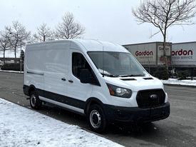 White 2021 Ford Transit van parked on a snowy surface with a sleek design and cargo area in the back