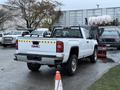 A white 2017 GMC Sierra 3500HD pickup truck with a black mesh bed cover and rear reflective markings is parked displaying its rear view