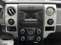 Dashboard of a 2014 Ford F-150 featuring an audio system display with various buttons and controls for media and climate settings