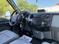 The interior of a 2013 Ford F-550 featuring a dashboard with audio controls a gear shift and leather seats