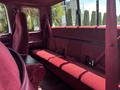 The interior of a 1995 Ford F-250 featuring red upholstery with a bench seat and seatbelts visible on the back seat