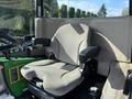 A John Deere 1575 tractor seat with a grey fabric cover and armrests positioned within the cabin of the tractor