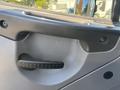 Close-up of the door handle of a 2005 Freightliner M2 106 featuring a textured grip and a smooth finish around the handle