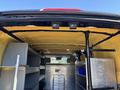 Interior of a 2016 Ford Transit 150 featuring shelving units a partition and equipment mounts